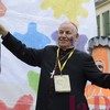 Una ruota arcobaleno, il microfono in mano e una guancia dipinta: è il vescovo Antonio alla Festa delle Palme!